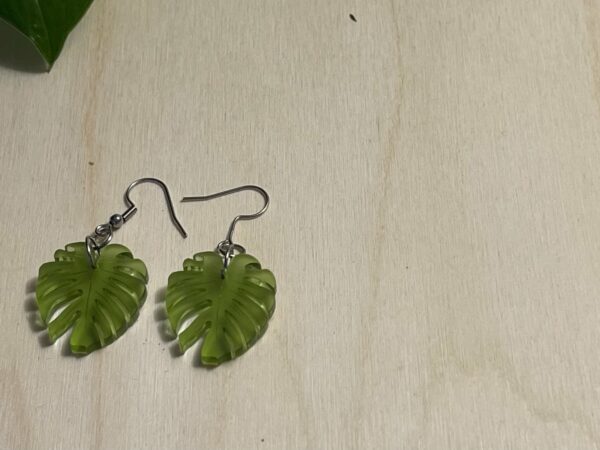 Acrylic moss green monstera leaf dangle earrings view from top