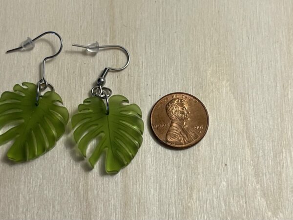 Acrylic moss green monstera leaf shown next to a penny for size