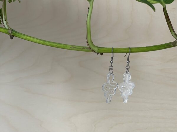 Acrylic clear snake dangle earrings, hanging from branch