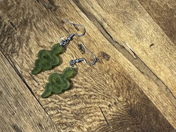 Acrylic moss green snake dangle earrings, lying flat