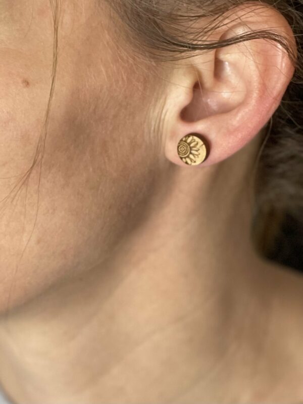 Wooden sunflower outline stud earrings in ear